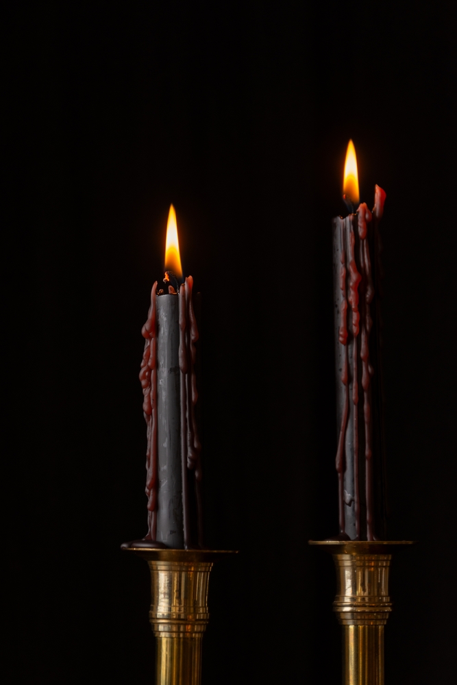 Closeup,Of,Two,Black,Candles,Burning,In,Golden,Candlestick,,Black