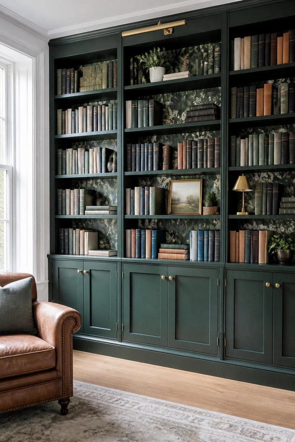 Deep green library shelves with dark botanical wallpaper and brass lamps in daylight