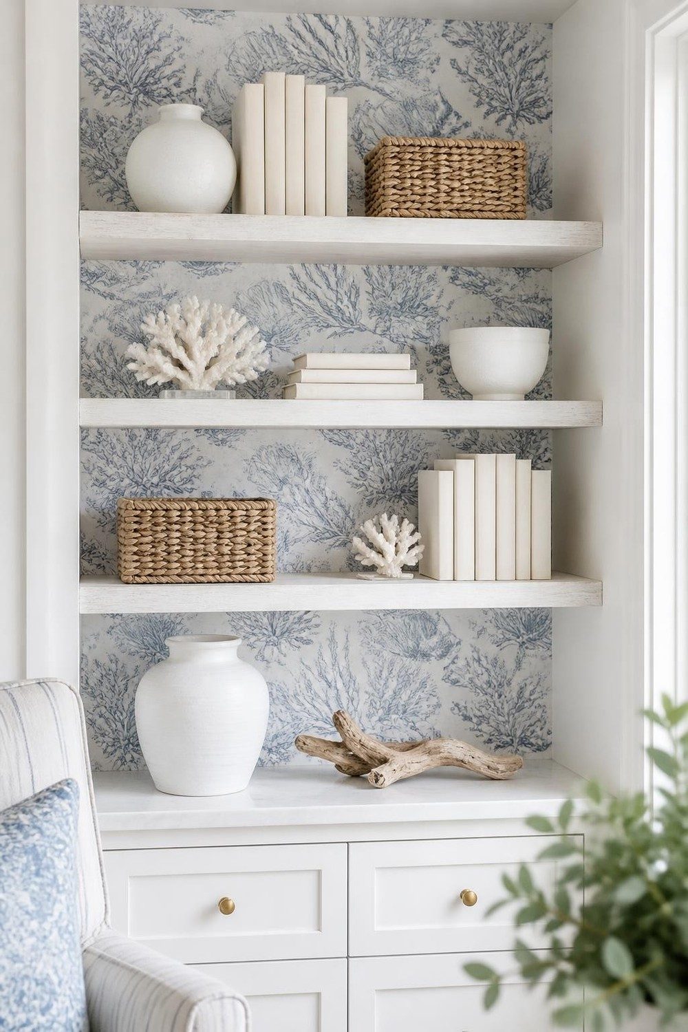 Coastal shelves against light blue seaside toile wallpaper with white pottery and coral