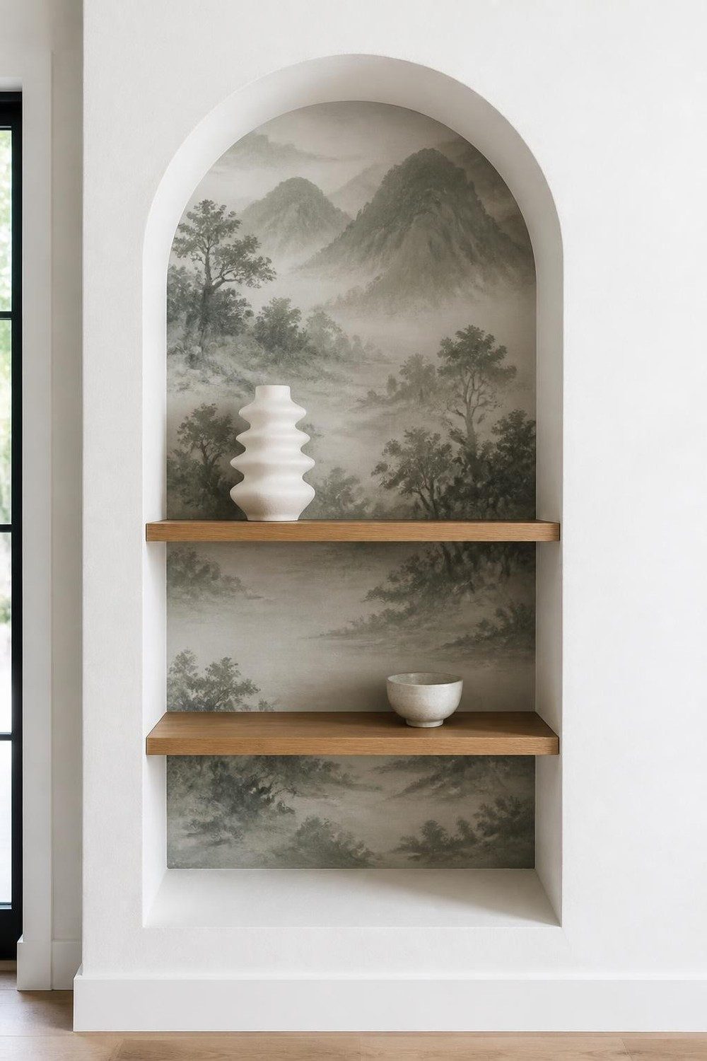 Arched niche lined with a misty mountain landscape mural and oak shelves
