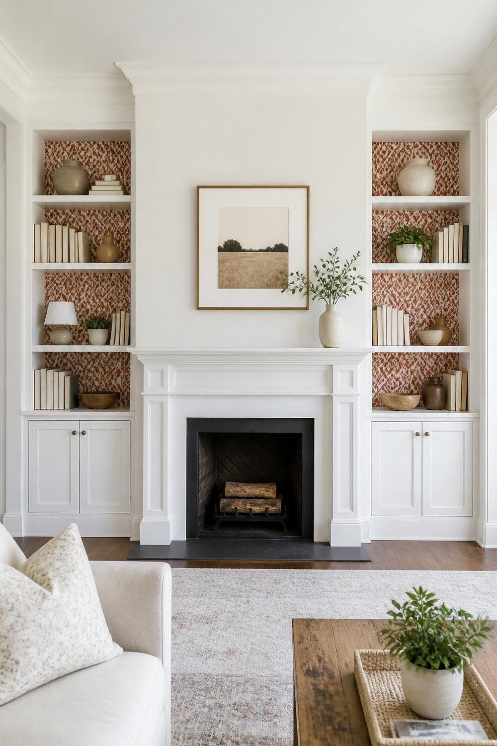 Two matching built-in bookcases flanking a fireplace, both lined with rust and cream ikat wallpaper